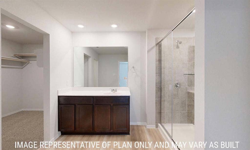 3213 Cyprian Road, Lorena, TX 76655 Bathroom featuring a dark wood-finish vanity, solid-surface countertop, full-width mirror, walk-in shower with glass enclosure, and built-in closet shelving