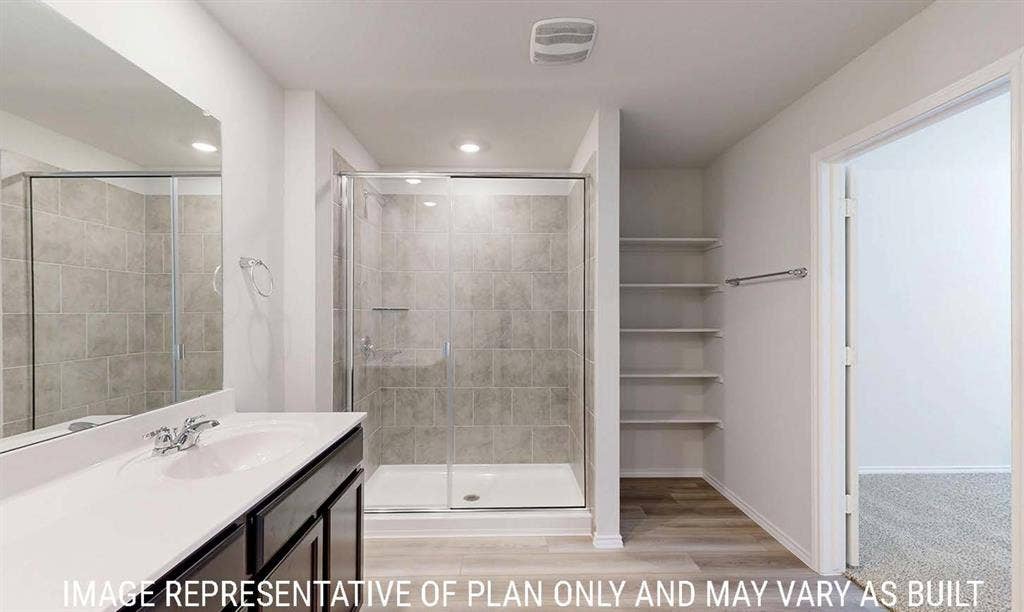 3213 Cyprian Road, Lorena, TX 76655 Bathroom featuring a walk-in shower with tile surround, glass enclosure, vanity with integrated sink, and built-in shelving