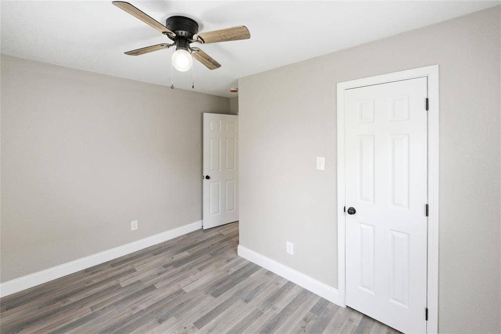 Neutral wall finishes, wood-finish flooring, and a ceiling fan with integrated lighting