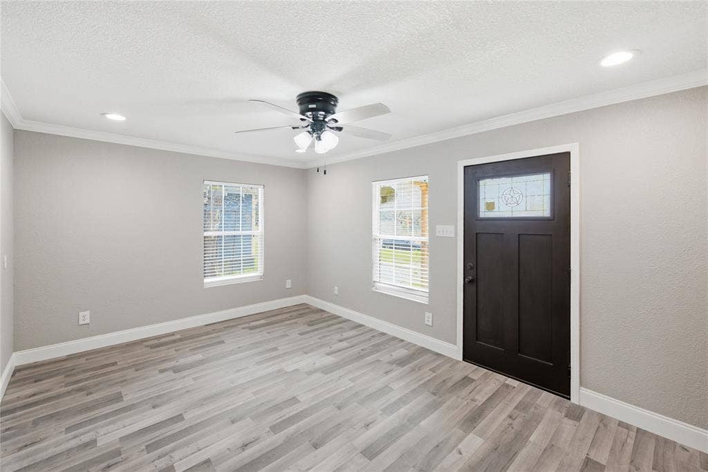 Interior space featuring wood-finish flooring, neutral wall paint, recessed lighting, a ceiling fan with integrated light fixture, and an exterior door with a decorative glass insert