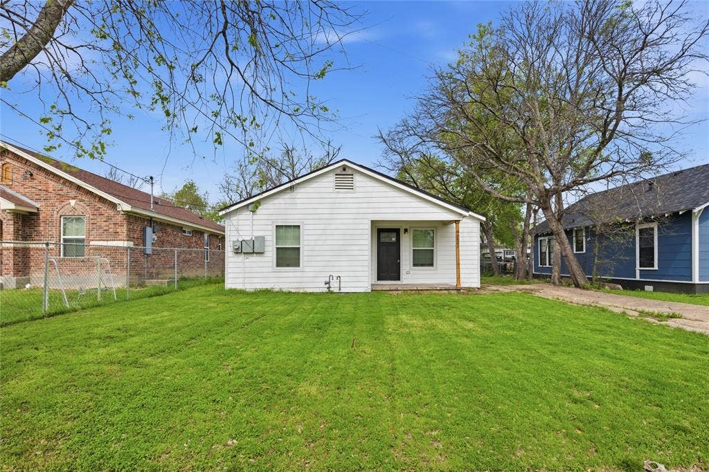 White siding exterior featuring a recessed entrance, asphalt shingle roof, double-hung windows, and an expansive grass yard