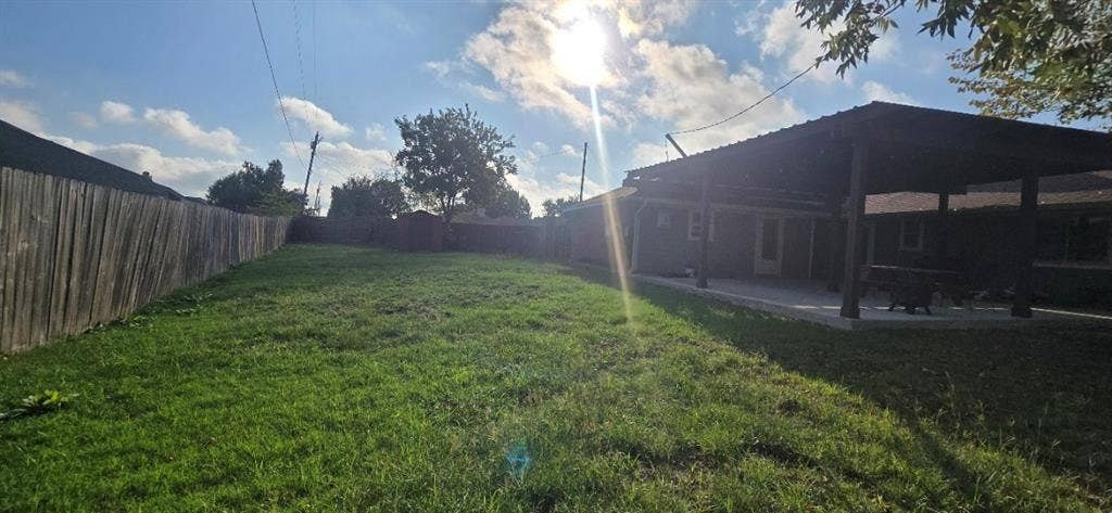 Spacious backyard featuring a covered patio, wood privacy fencing, and a detached storage shed