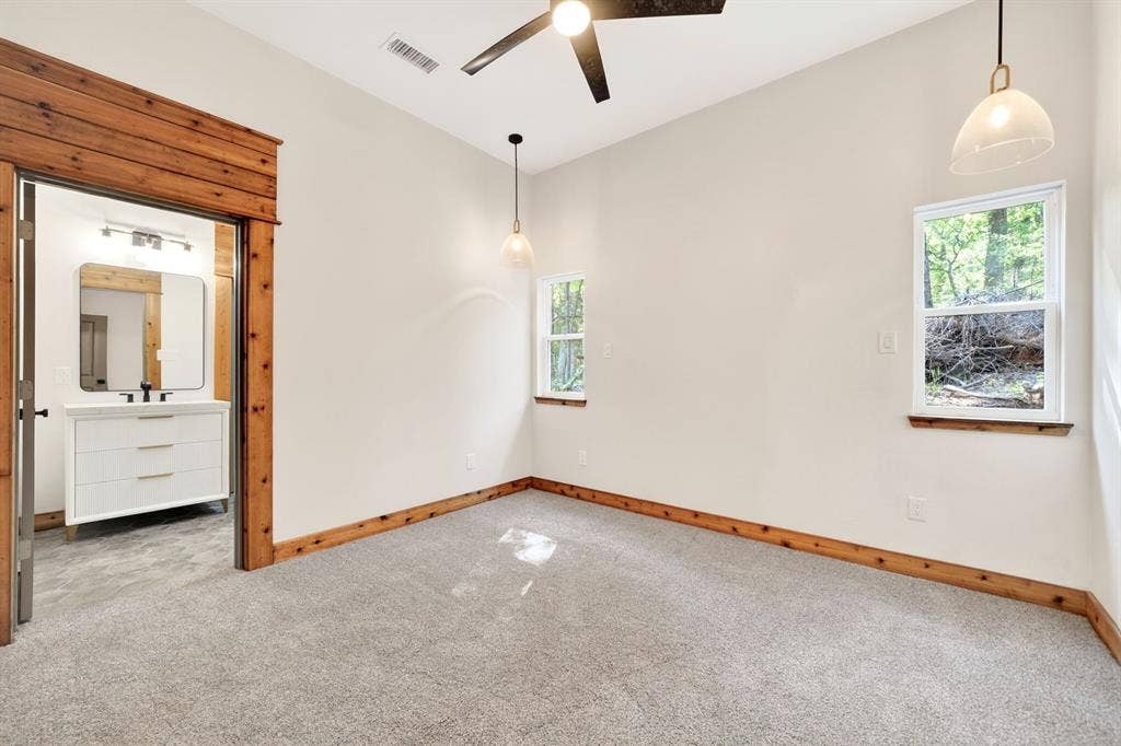 116 Carolynn Road, Mabank, TX 75156 Interior space featuring wood trim accents, neutral wall-to-wall carpeting, dual hanging pendant light fixtures, and a matte black ceiling fan