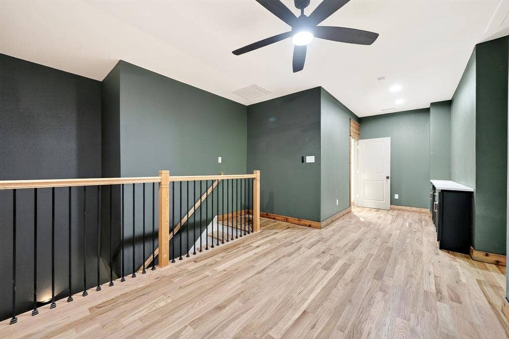 116 Carolynn Road, Mabank, TX 75156 Open loft space featuring wood-finish flooring, a wood and metal balustrade, recessed lighting, a modern ceiling fan, and built-in cabinetry