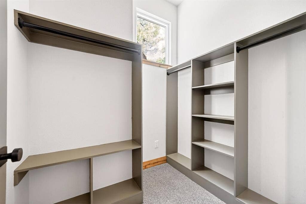 116 Carolynn Road, Mabank, TX 75156 Custom storage system featuring neutral-toned cabinetry, built-in shelving, integrated garment rods, and a window allowing for natural light