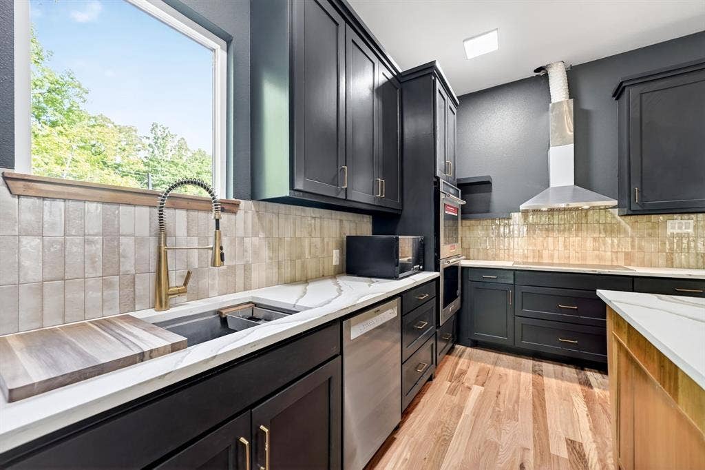 116 Carolynn Road, Mabank, TX 75156 Kitchen featuring dark cabinetry, stone-surface countertops, textured vertical tile backsplash, stainless steel appliances, and wood-finish flooring