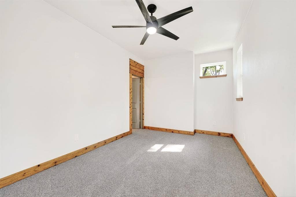 116 Carolynn Road, Mabank, TX 75156 Neutral interior featuring wall-to-wall carpeting, matte black ceiling fan with integrated lighting, wood-trim doorway and window sills, and dual windows