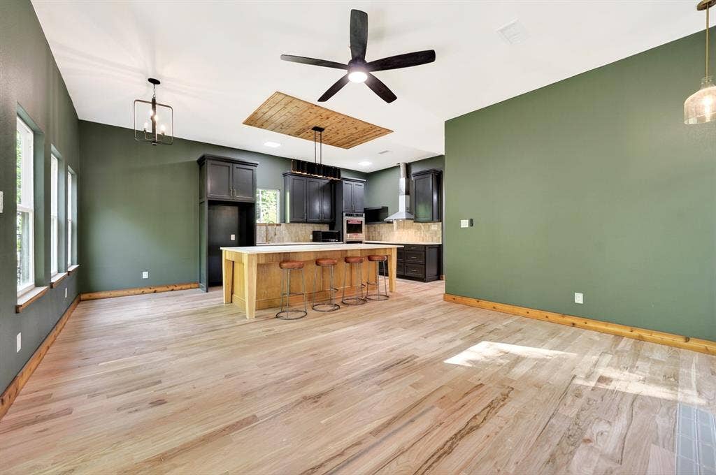 116 Carolynn Road, Mabank, TX 75156 Kitchen featuring a wood-topped center island, custom dark cabinetry, wood-finish flooring, vaulted ceiling with wood paneling inlay, and integrated stainless steel appliances