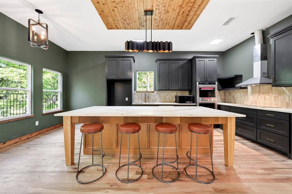 116 Carolynn Road, Mabank, TX 75156 Kitchen featuring a central island with a stone countertop, wood-finish cabinetry, built-in double oven, stainless steel range hood, and a ceiling inset with wood-plank detailing