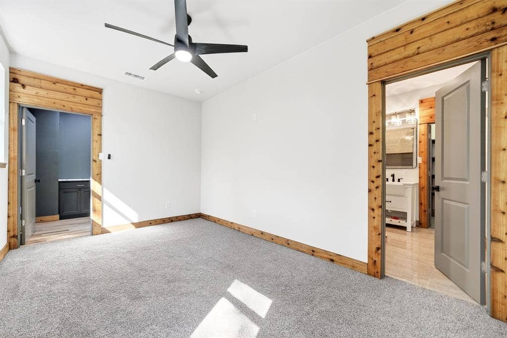116 Carolynn Road, Mabank, TX 75156 Room featuring neutral wall-to-wall carpeting, natural wood door casing, grey interior doors, and a modern matte black ceiling fan with integrated lighting