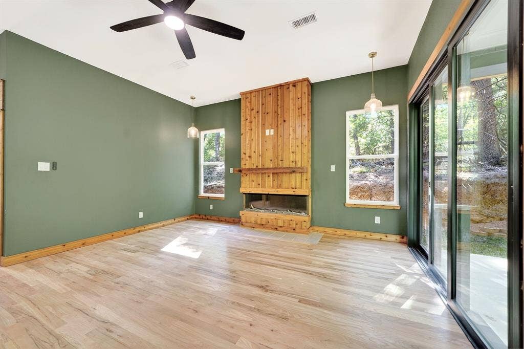 116 Carolynn Road, Mabank, TX 75156 Living area featuring wood-finish flooring, a floor-to-ceiling wood-clad fireplace, integrated ceiling fan, and sliding glass doors