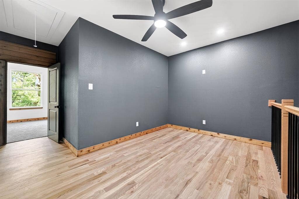 116 Carolynn Road, Mabank, TX 75156 Wood-finish flooring, dark-toned interior walls, natural wood trim, matte black ceiling fan, and staircase with wooden handrail and black metal balusters