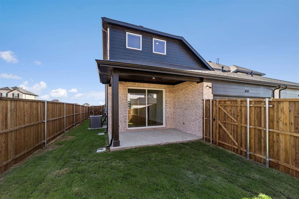 11512 Empress Drive, Frisco, TX 75035 Rear exterior featuring a covered concrete patio, brick and horizontal siding facade, sliding glass door, and full wood privacy fencing