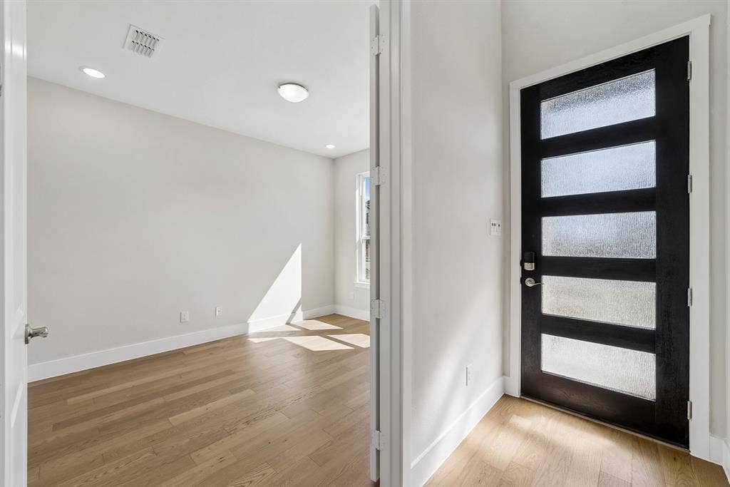 11512 Empress Drive, Frisco, TX 75035 Modern entry featuring a black five-panel door with textured glass inserts, light wood-finish flooring, and recessed ceiling lighting