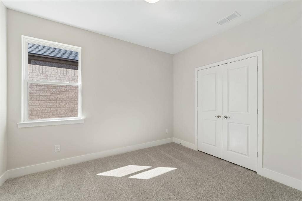 11512 Empress Drive, Frisco, TX 75035 Neutral-toned room featuring plush wall-to-wall carpeting, dual-panel interior closet doors, and a single-pane window with brick exterior detail