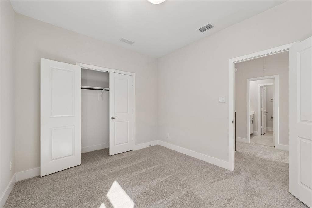 11512 Empress Drive, Frisco, TX 75035 Neutral-toned interior room featuring wall-to-wall carpeting, a reach-in closet with double-panel doors, and a ceiling-mounted light fixture