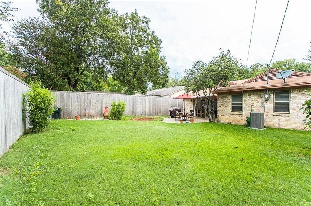 1217 Cloverdale Drive, Richardson, TX 75080 Backyard featuring a privacy fence, concrete patio, masonry exterior, and mature landscaping
