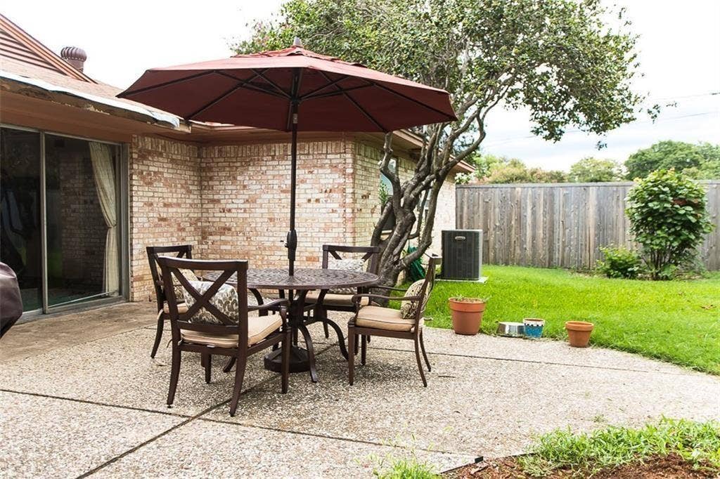 1217 Cloverdale Drive, Richardson, TX 75080 Concrete patio featuring a brick exterior wall, sliding glass doors, and a wood privacy fence