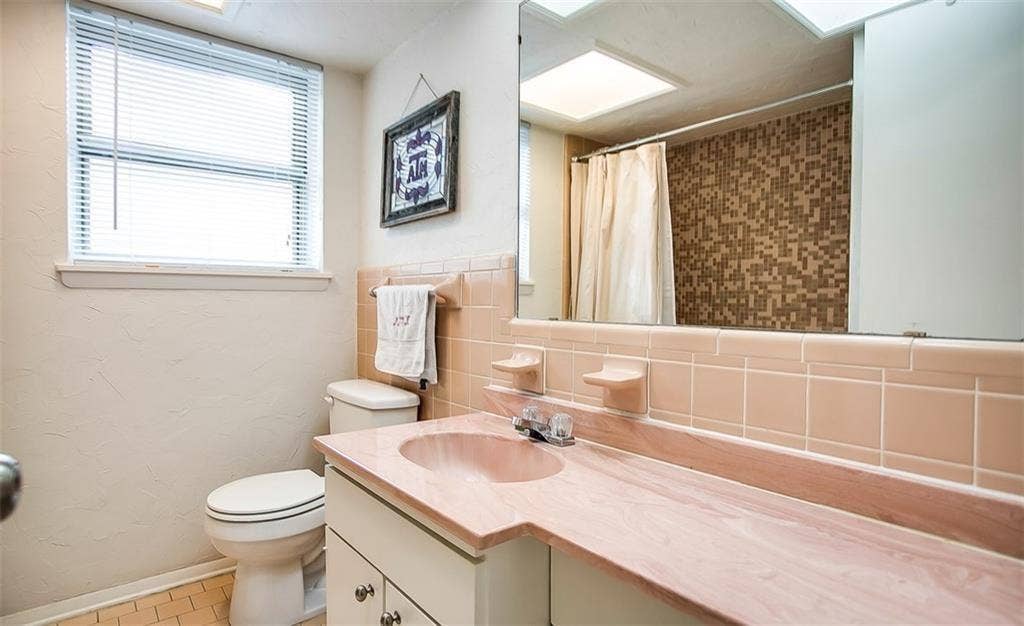 1217 Cloverdale Drive, Richardson, TX 75080 Bathroom featuring a vanity with an integrated basin, a large wall-mounted mirror, ceramic tile backsplashes, a shower with patterned tile surround, and a window with integrated blinds