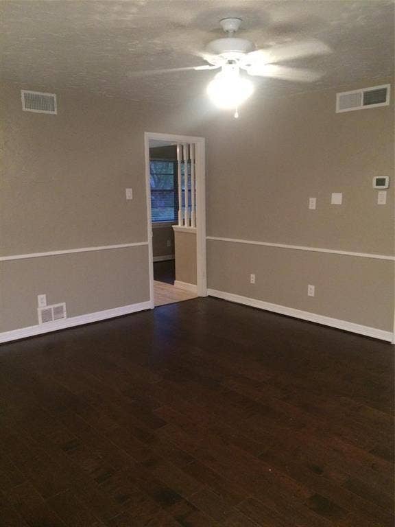 1217 Cloverdale Drive, Richardson, TX 75080 Interior space featuring dark wood-finish flooring, neutral wall tones, white chair rail molding, a ceiling fan with integrated lighting, and decorative balusters