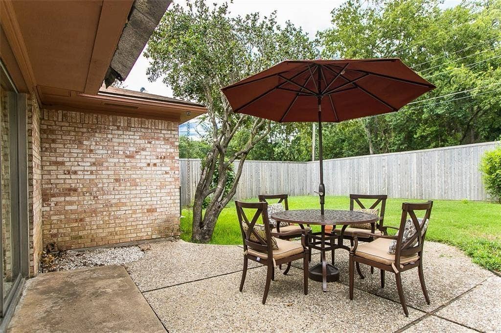 1217 Cloverdale Drive, Richardson, TX 75080 Concrete patio with brick exterior wall, mature trees, and wooden privacy fencing