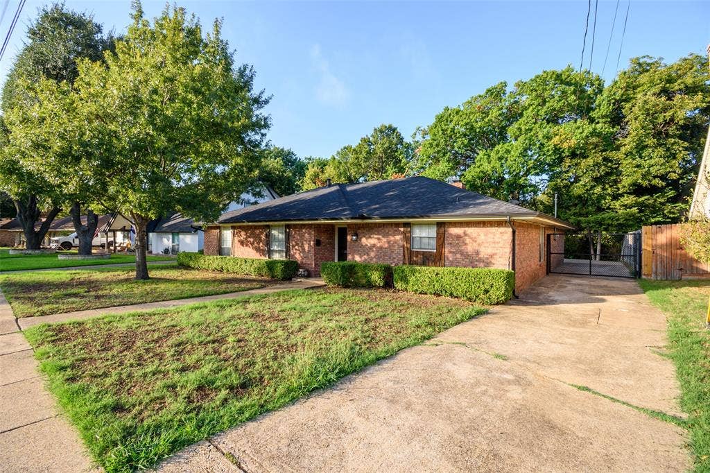 286 Larry Drive, Dallas, TX 75137 Single-story brick exterior with a dark-toned roof, concrete driveway, and established landscaping