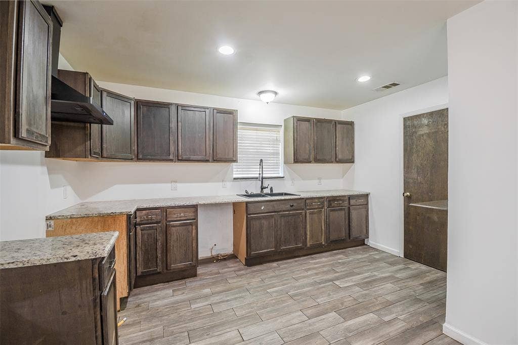 286 Larry Drive, Dallas, TX 75137 Kitchen featuring dark-toned cabinetry, stone-finish countertops, wood-finish flooring, recessed lighting, and a gooseneck faucet