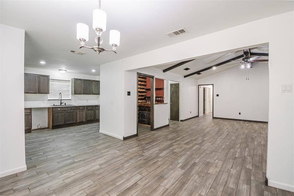 286 Larry Drive, Dallas, TX 75137 Kitchen featuring stained wood cabinetry, white countertops, and a pendant chandelier, complemented by wood-finish flooring throughout the interior with exposed ceiling beams