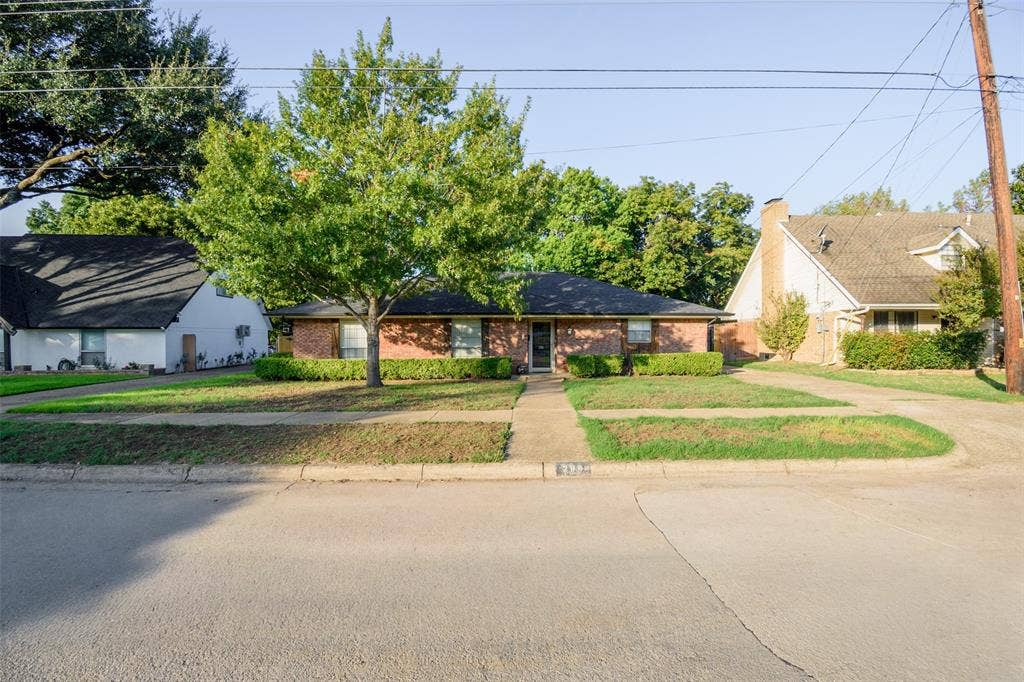 286 Larry Drive, Dallas, TX 75137 Single-story brick exterior featuring a low-pitch roof, mature landscaping, and a centered concrete walkway