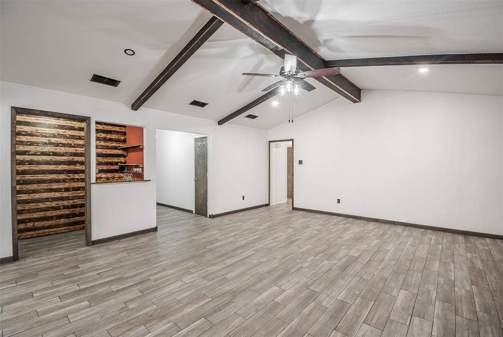 286 Larry Drive, Dallas, TX 75137 Vaulted ceiling with exposed wood beams, wood-finish tile flooring, recessed lighting, and a built-in architectural accent wall