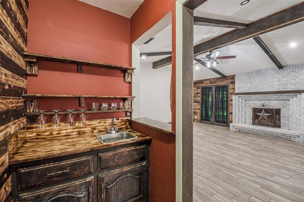 286 Larry Drive, Dallas, TX 75137 Built-in wet bar featuring custom wood cabinetry, wood-finish countertops, floating shelving, and an inset stainless steel sink