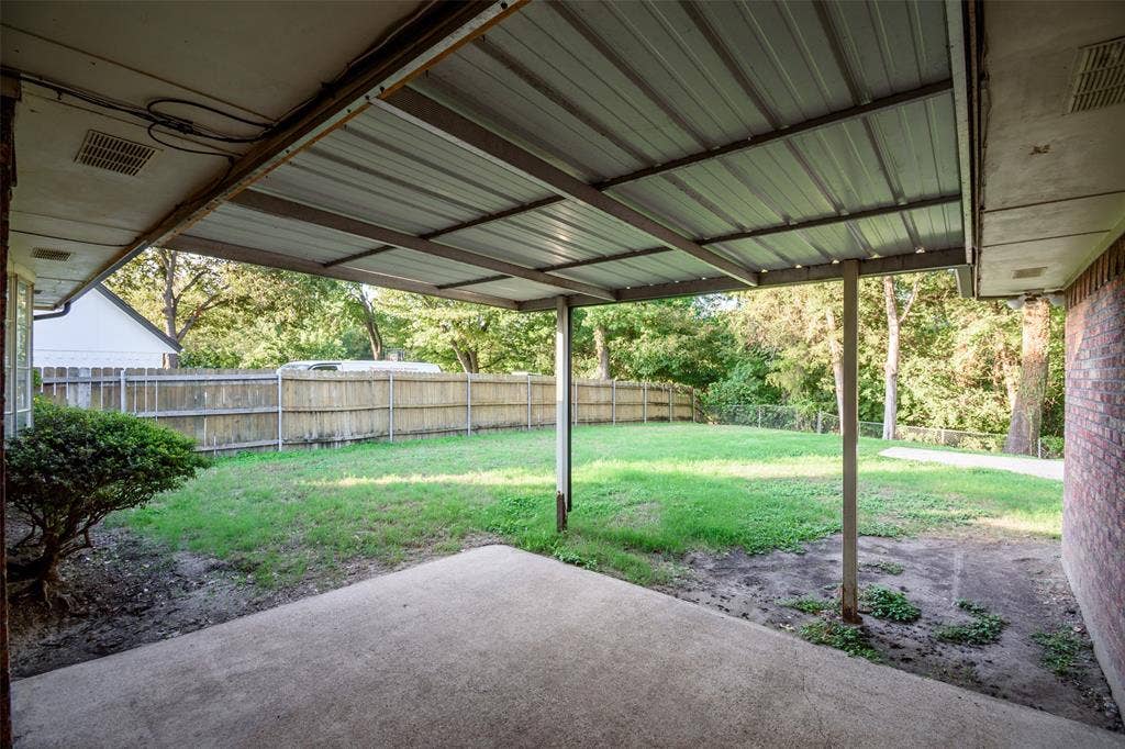 286 Larry Drive, Dallas, TX 75137 Covered patio with a metal roof, concrete flooring, brick exterior wall, and fenced backyard