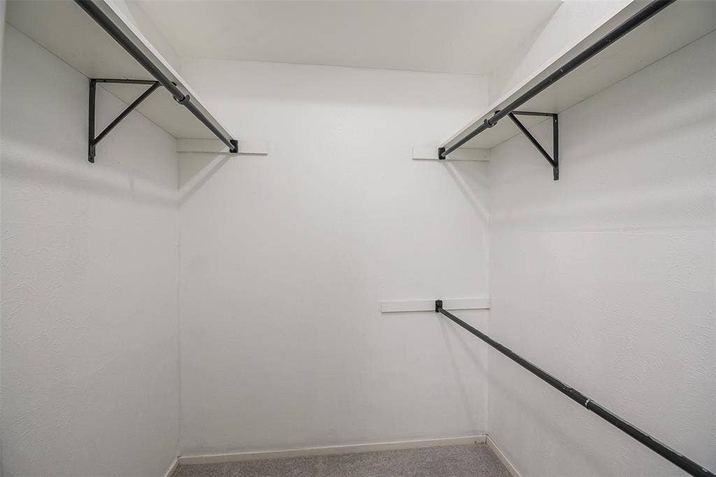 286 Larry Drive, Dallas, TX 75137 Storage closet featuring dual-level white shelving and matte black metal hanging rods