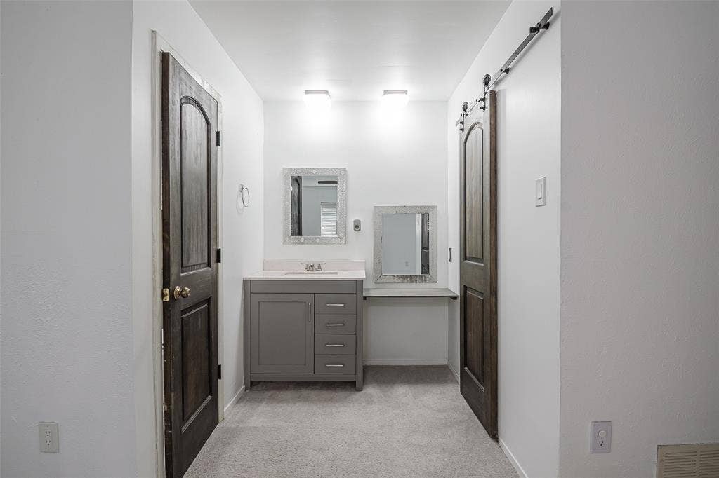 286 Larry Drive, Dallas, TX 75137 Grey vanity with countertop, integrated sink, and built-in storage, side counter extension, and dark wood-finish doors