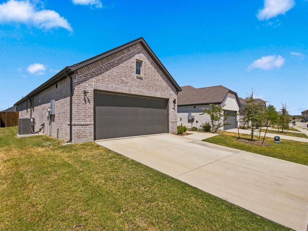 1157 Butterfly Dale Drive, Lavon, TX 75166 Brick exterior, gabled roofline, concrete driveway, and attached two-car garage