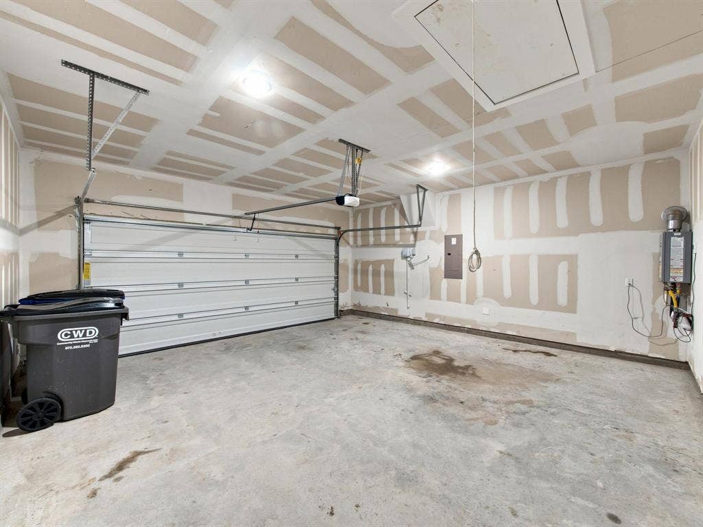 1157 Butterfly Dale Drive, Lavon, TX 75166 Attached garage featuring a concrete floor, an overhead sectional garage door, flush-mount ceiling lighting, and an attic access panel