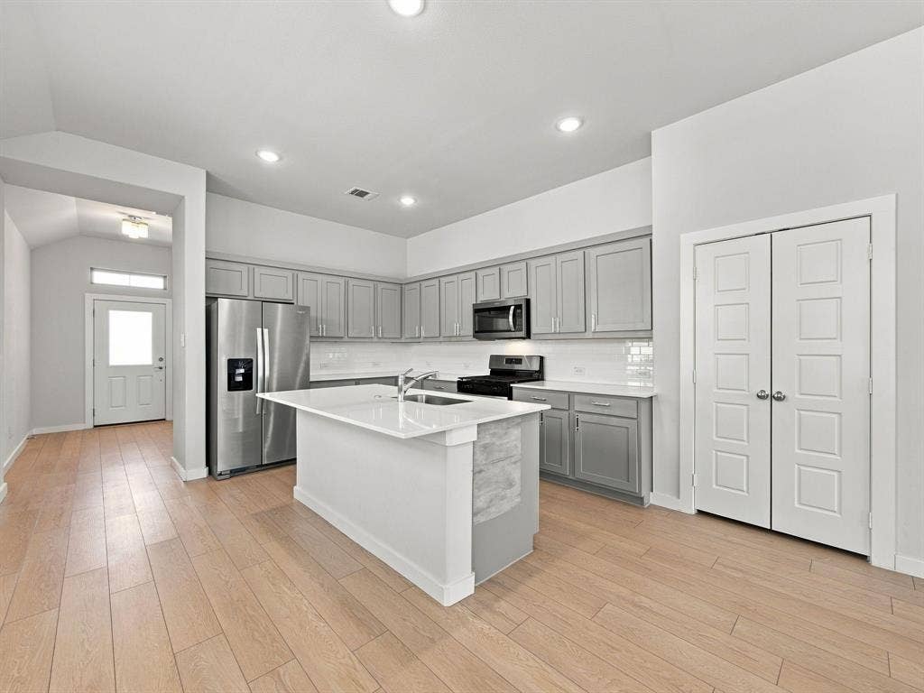 1157 Butterfly Dale Drive, Lavon, TX 75166 Kitchen featuring a central island with a solid surface countertop, light-toned wood-finish flooring, shaker-style cabinetry, recessed lighting, and stainless steel appliances