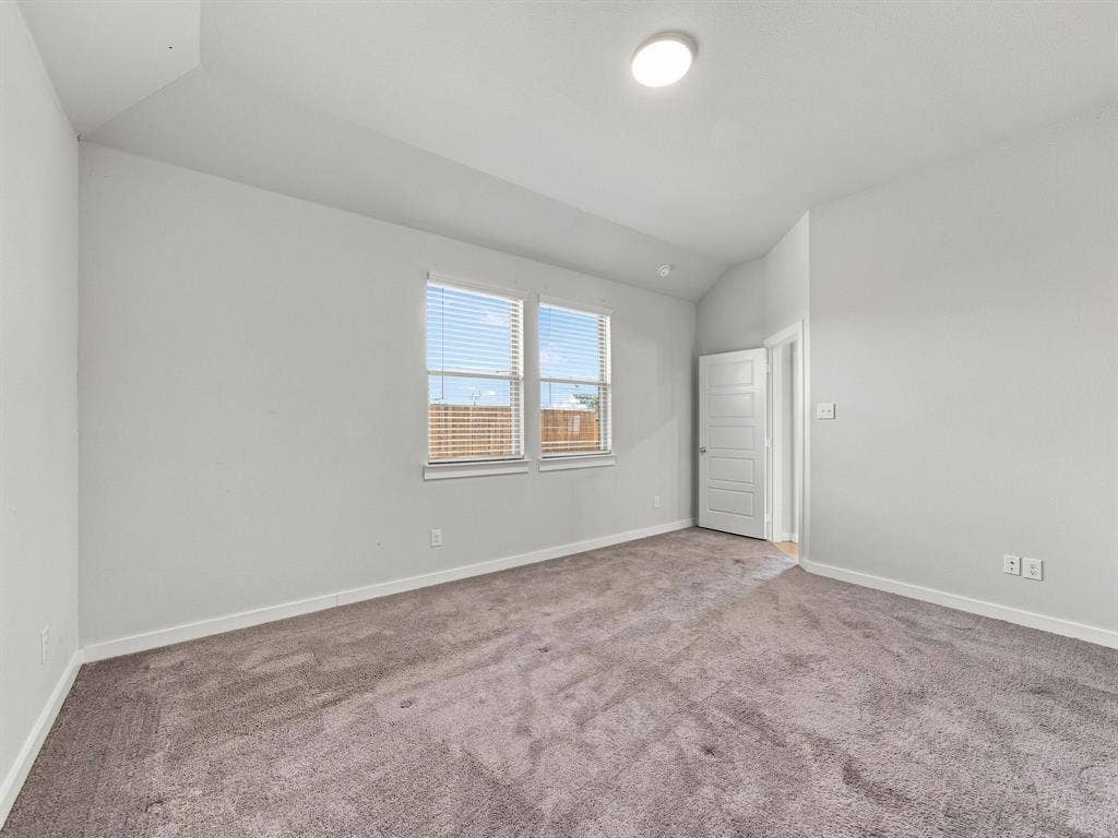 1157 Butterfly Dale Drive, Lavon, TX 75166 Neutral-toned room featuring a vaulted ceiling, plush wall-to-wall carpeting, two double-hung windows with horizontal blinds, and a paneled interior door