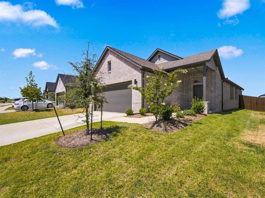 1157 Butterfly Dale Drive, Lavon, TX 75166 Single-story residence featuring a brick exterior, gabled rooflines, attached two-car garage, concrete driveway, and landscaped front lawn