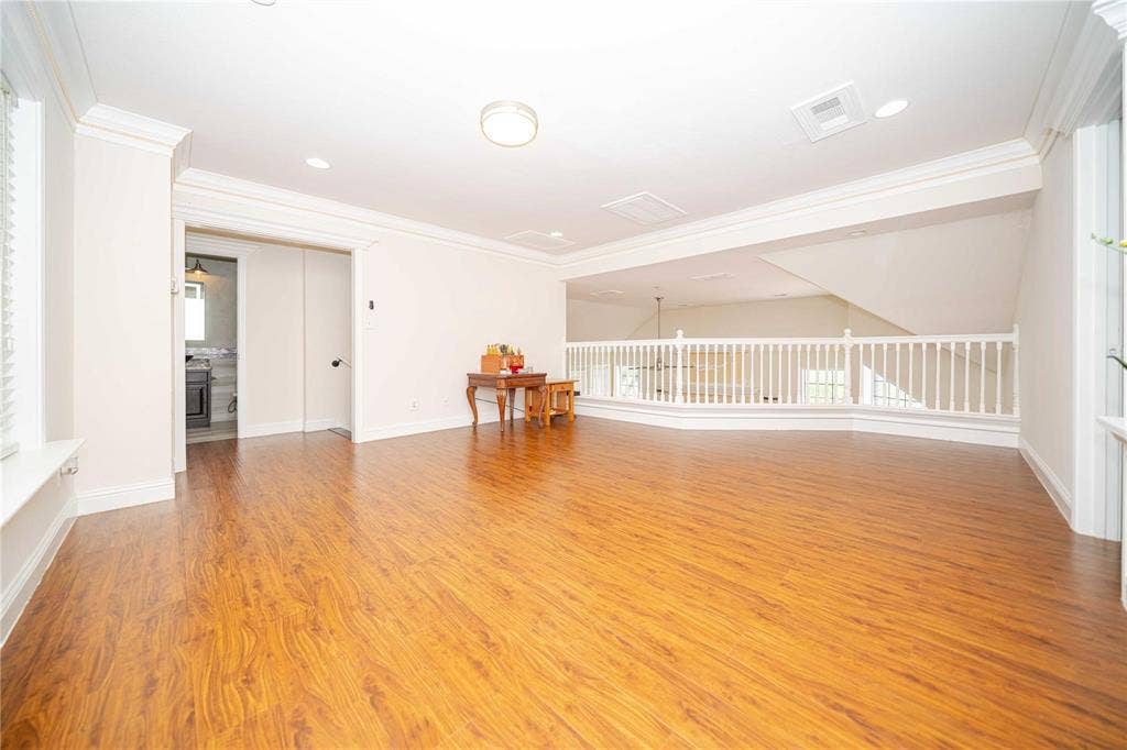 Open loft area featuring wood-finish flooring, crown molding, recessed lighting, and a white balustrade railing