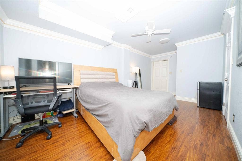 Wood-finish flooring, crown molding, ceiling fan, and six-panel interior door