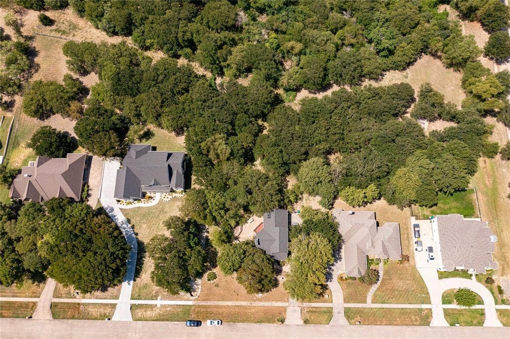 Aerial perspective featuring multi-structure residential lots with concrete driveways and dense, mature tree coverage