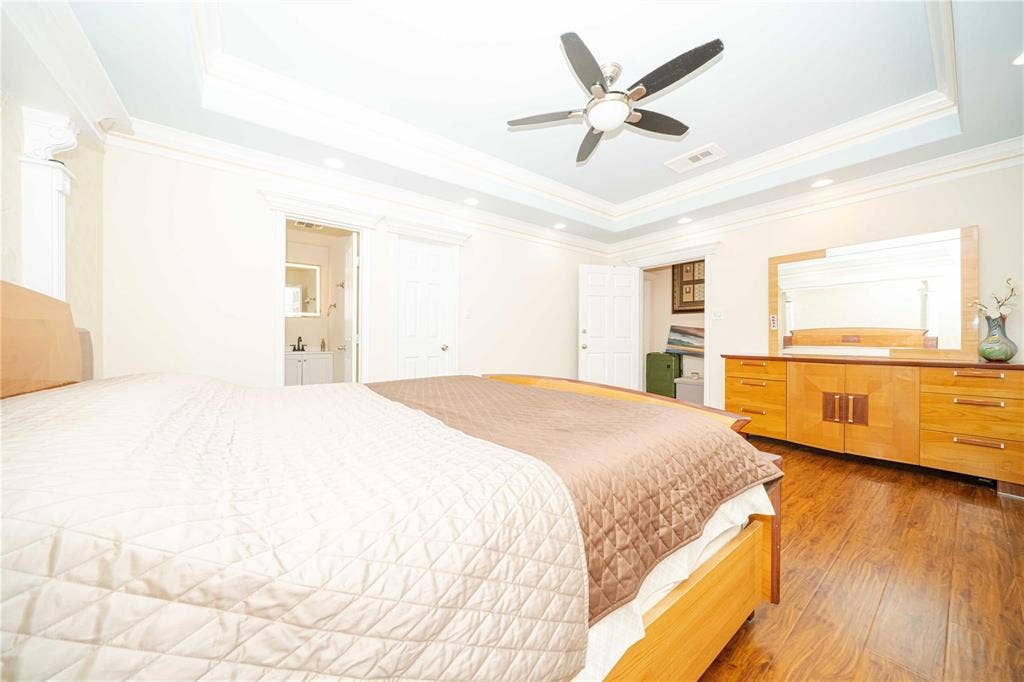 Tray ceiling with recessed lighting, wood-finish flooring, and ceiling fan with integrated light fixture