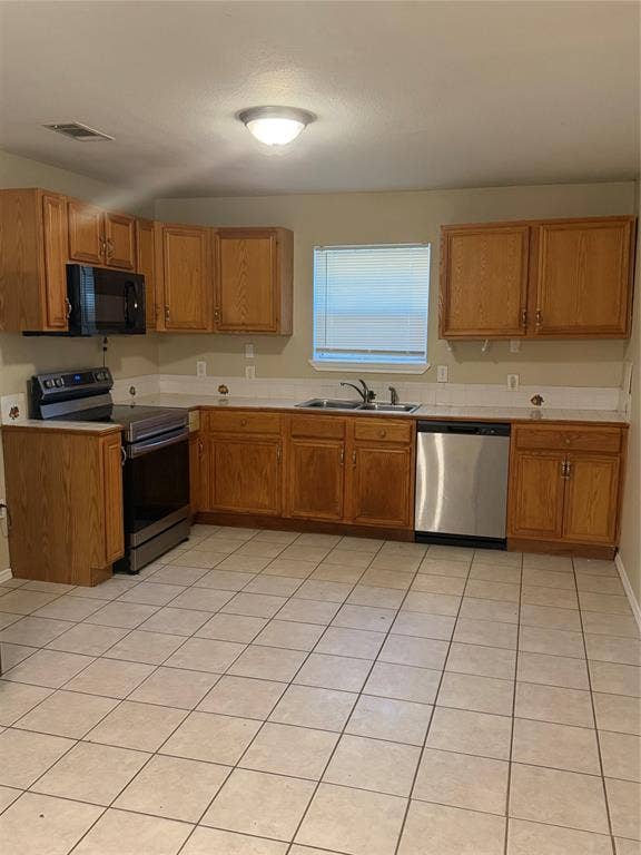 475 Perch Road, Rockwall, TX 75032 Kitchen featuring wood cabinetry, stainless steel appliances, tile flooring, a dual-basin sink, and a tiled backsplash