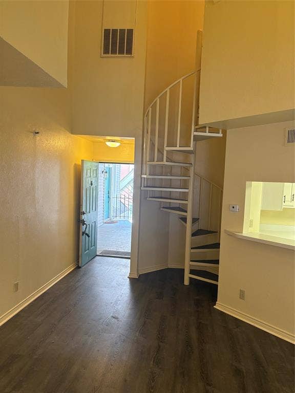 1010 Allen Street, #222, Dallas, TX 75204 High-ceiling interior featuring wood-finish flooring, a white metal spiral staircase, and a pass-through opening to the kitchen