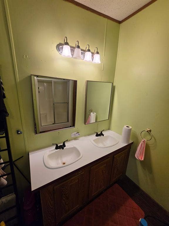 Dual-basin vanity featuring integrated sinks, laminate countertop, wood-finish cabinetry, and matte black hardware, accompanied by two wall-mounted mirrors and a four-light fixture