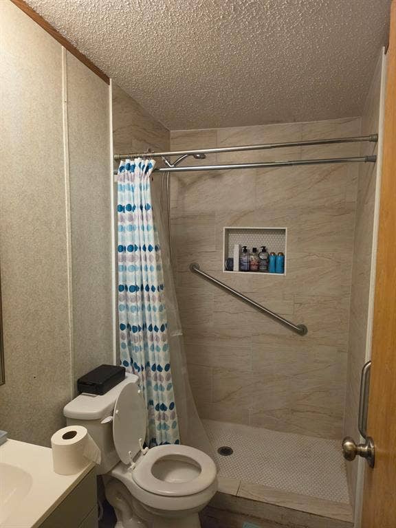 Walk-in shower featuring light-toned ceramic wall tile, mosaic floor tile, built-in recessed niche, and an installed metal grab bar