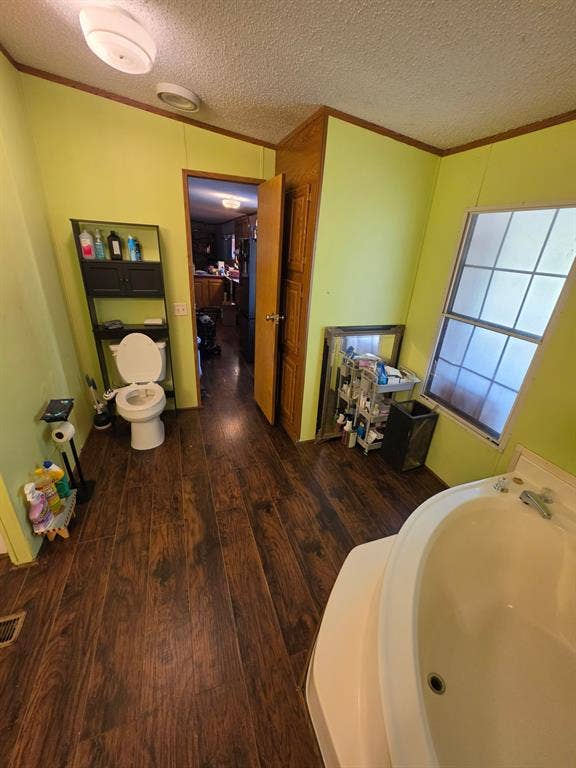 Bathroom featuring wood-finish flooring, a large soaking tub, and a window with a grid pattern