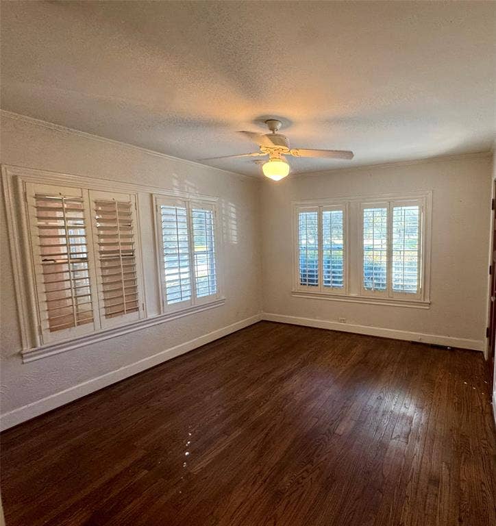 Room featuring wood-finish flooring, plantation shutters, and a ceiling-mounted light fixture with fan