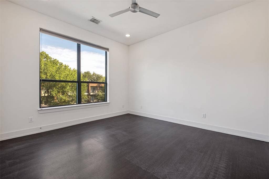 3336 Anchor Court, Dallas, TX 75219 Dark wood-finish flooring, crisp white walls, large black-framed window, and a modern ceiling fan